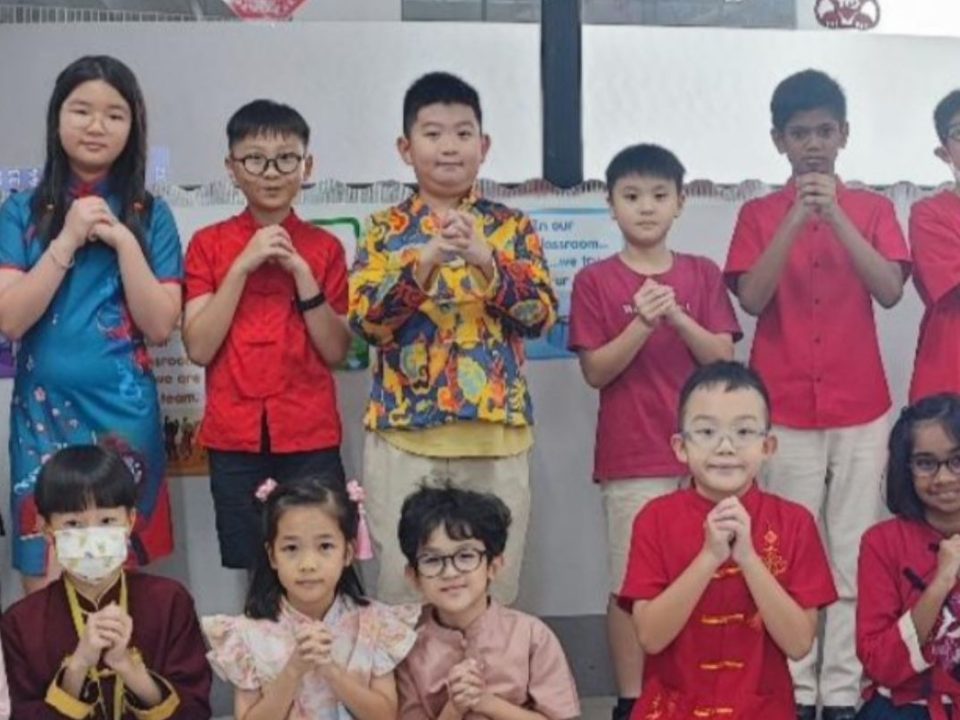 Primary school students joyfully celebrate Lunar New Year in vibrant red attire.