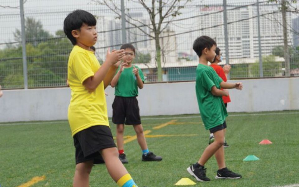 Primary School students start their PE lesson with a fun warm up during Odd Socks Week