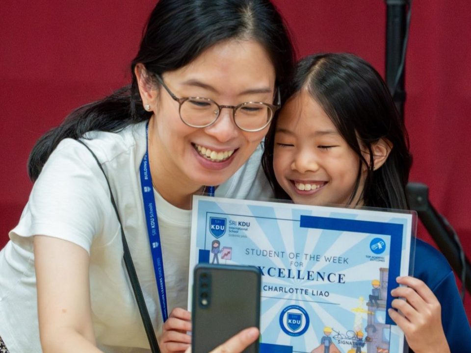 Parent and student taking photo of themselves celebrating student's achievement of excellence.